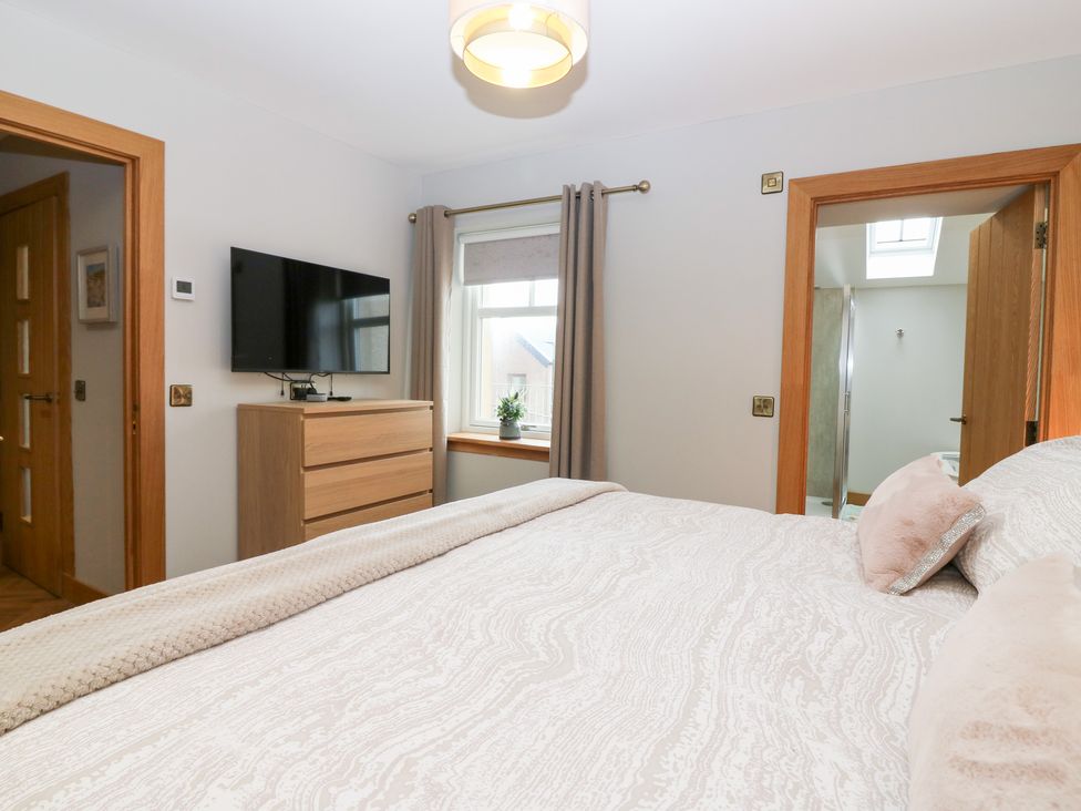 A bedroom with a bed and television at The Old Kipper Hoose in Banff
