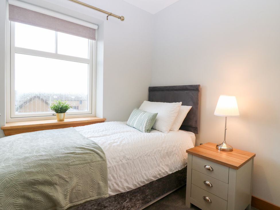 A bedroom with a bed and bedside table at The Old Kipper Hoose in Banff