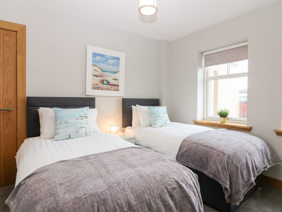 A bedroom with two beds and a window at The Old Kipper Hoose in Banff