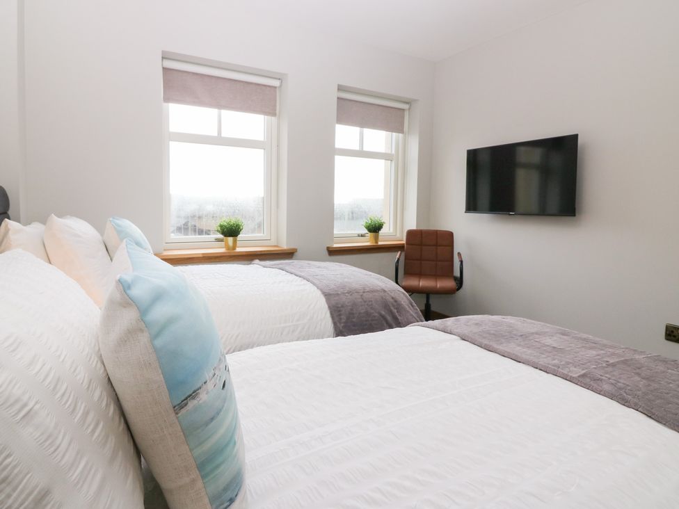 A bedroom with two beds and a television at The Old Kipper Hoose in Banff