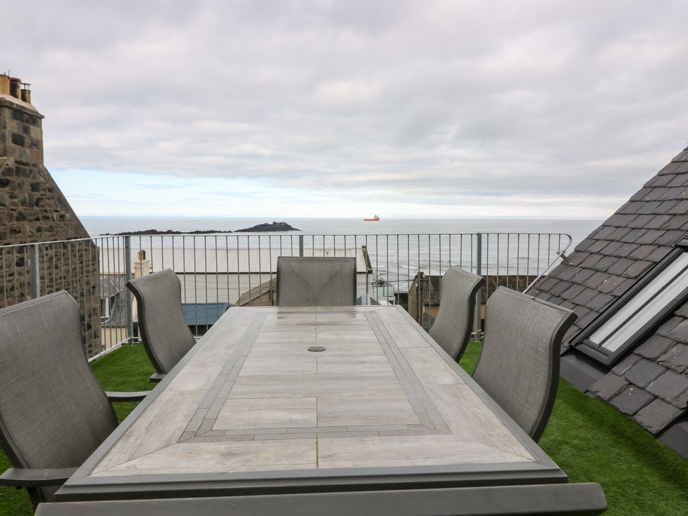 An outdoor dining area with a table and chairs overlooking the ocean at The Old Kipper Hoose in Banff