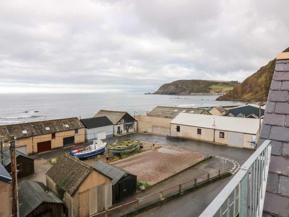 A coastal view with buildings and a boat at The Old Kipper Hoose in Banff