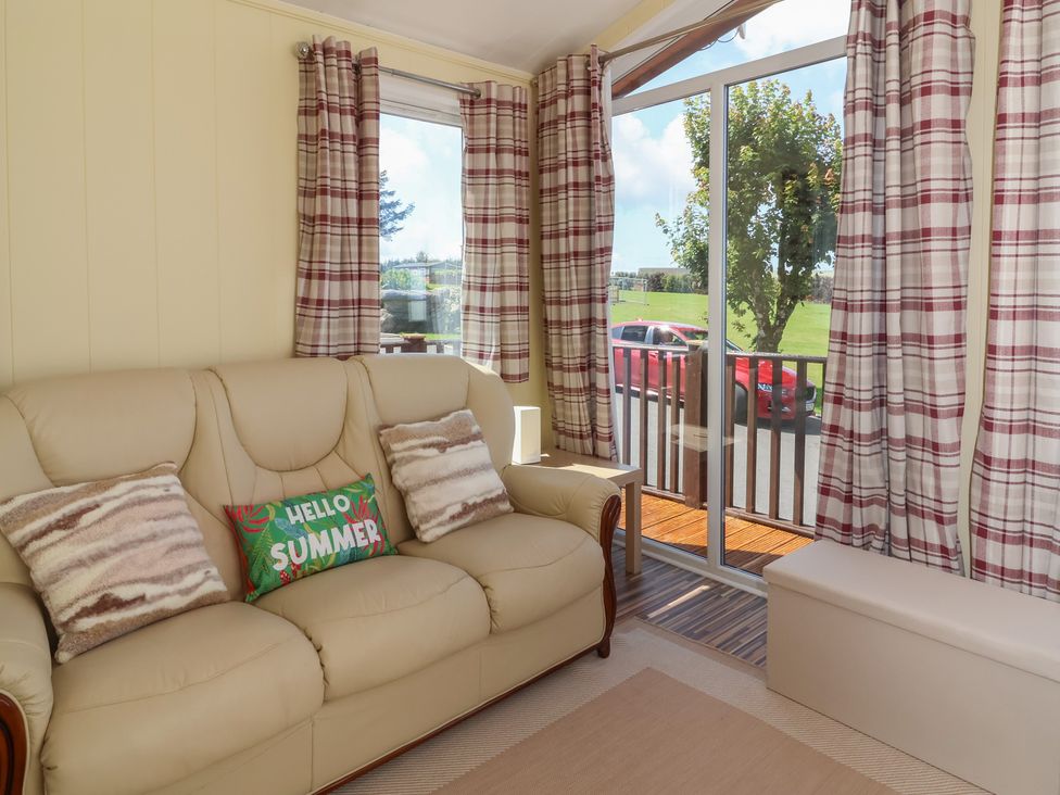 A living room with a sofa and curtains at Cody Cottage Lodge near Mullacott Park near Ilfracombe