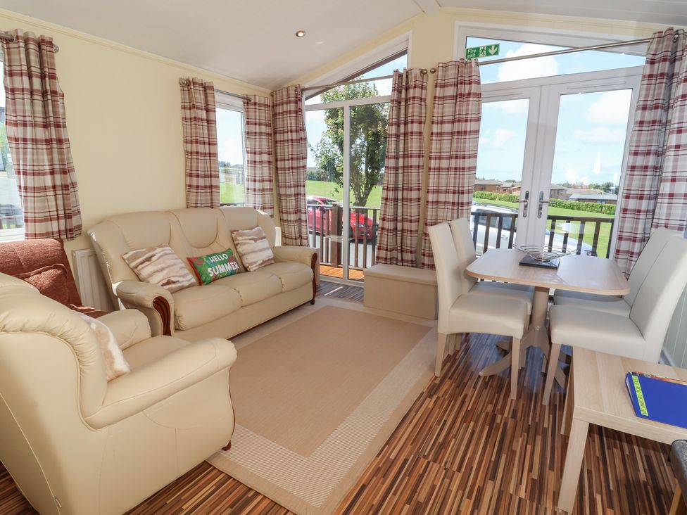 A living room with a sofa and dining area at Cody Cottage Lodge near Mullacott Park