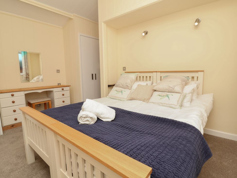 A bedroom with a bed and dresser at Cody Cottage Lodge in Mullacott Park near Ilfracombe