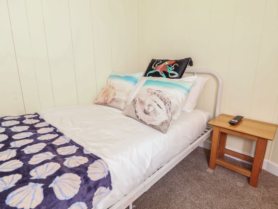 A bedroom with a bed and pillows on the Cody Cottage Lodge in Mullacott Park near Ilfracombe