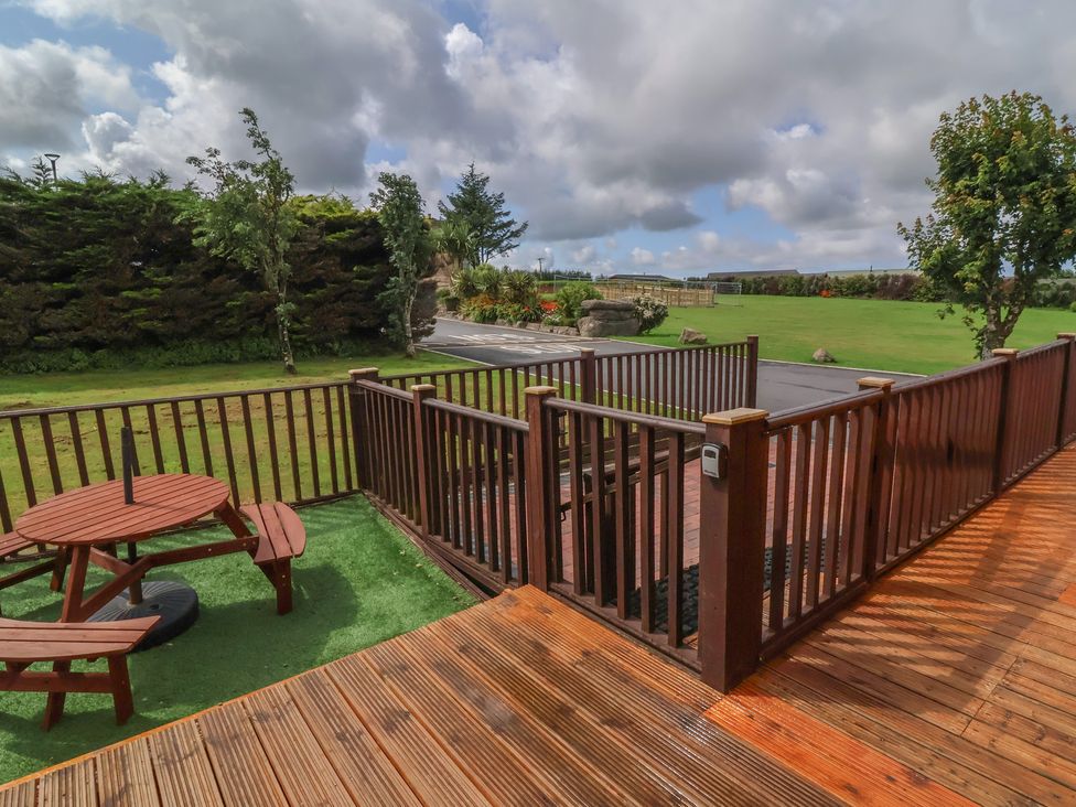 An outdoor seating area with a wooden table in the garden at Cody Cottage Lodge Mullacott Park near Ilfracombe
