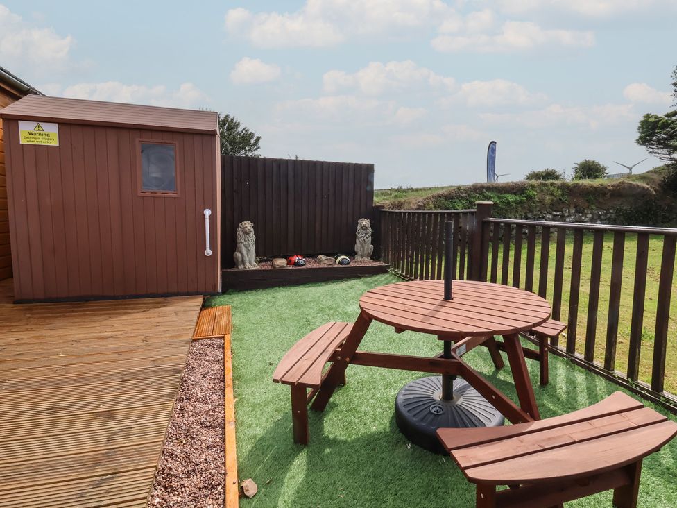 A garden with a table and shed at Cody Cottage Lodge Mullacott Park near Ilfracombe