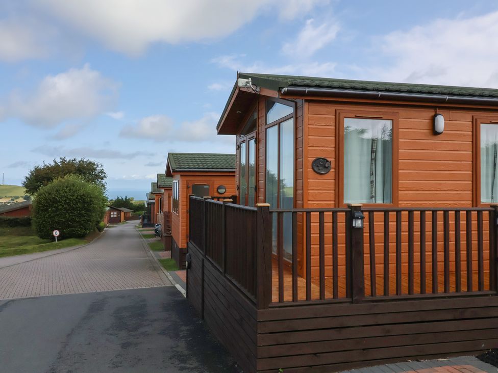 A holiday lodge with a balcony along a road at Cody Cottage Lodge Mullacott Park near Ilfracombe