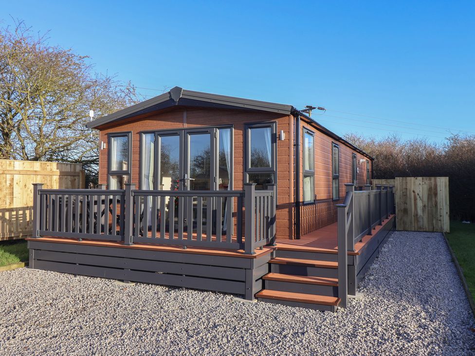 A wooden lodge with a deck and steps at Meadows Park 1 Great Hatfield near Hornsea