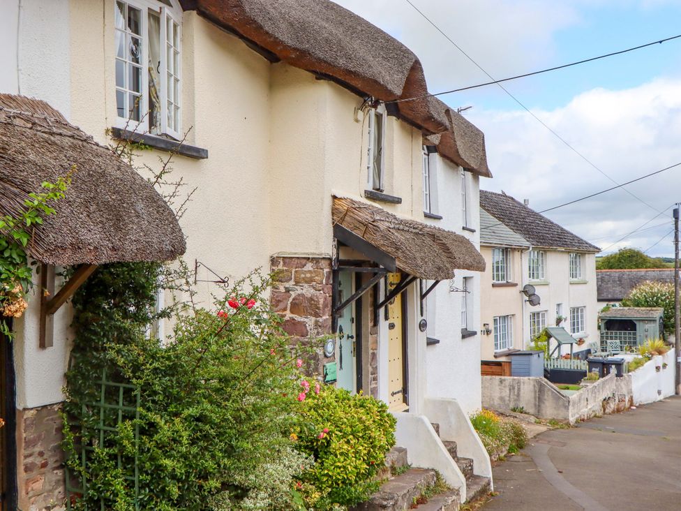 A view of a building with a thatched roof and garden at Cosy Nook South Molton