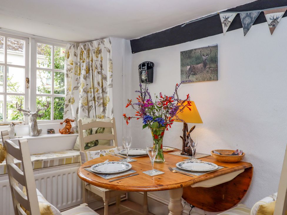 A dining room with a wooden table and floral curtains at Cosy Nook in South Molton