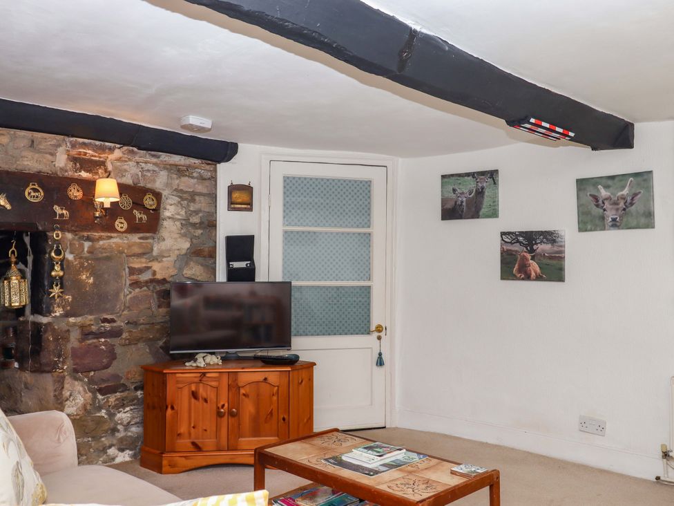 A living room with a television and a wooden table at Cosy Nook in South Molton