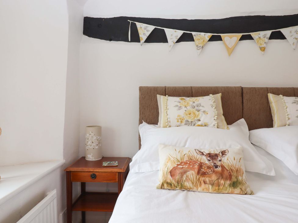 A bedroom with a bed, pillows, and a bedside table at Cosy Nook South Molton