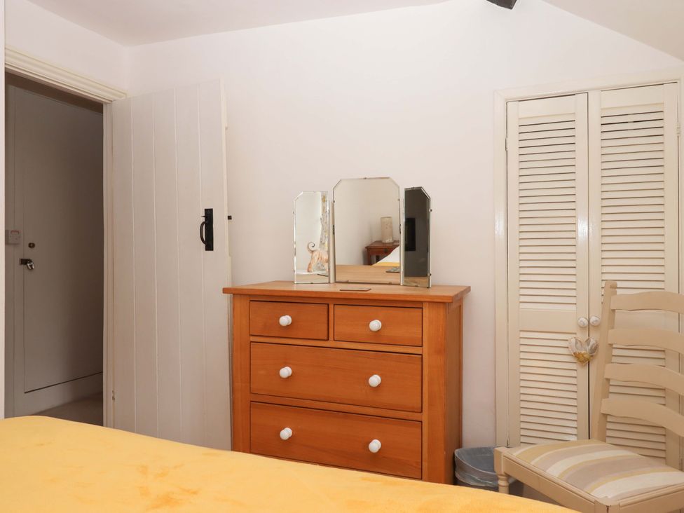A bedroom with a dresser, mirror and chair at Cosy Nook in South Molton