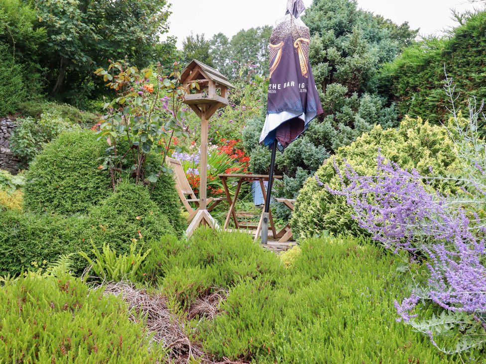A garden with a table, chairs and a bird feeder at Cosy Nook in South Molton