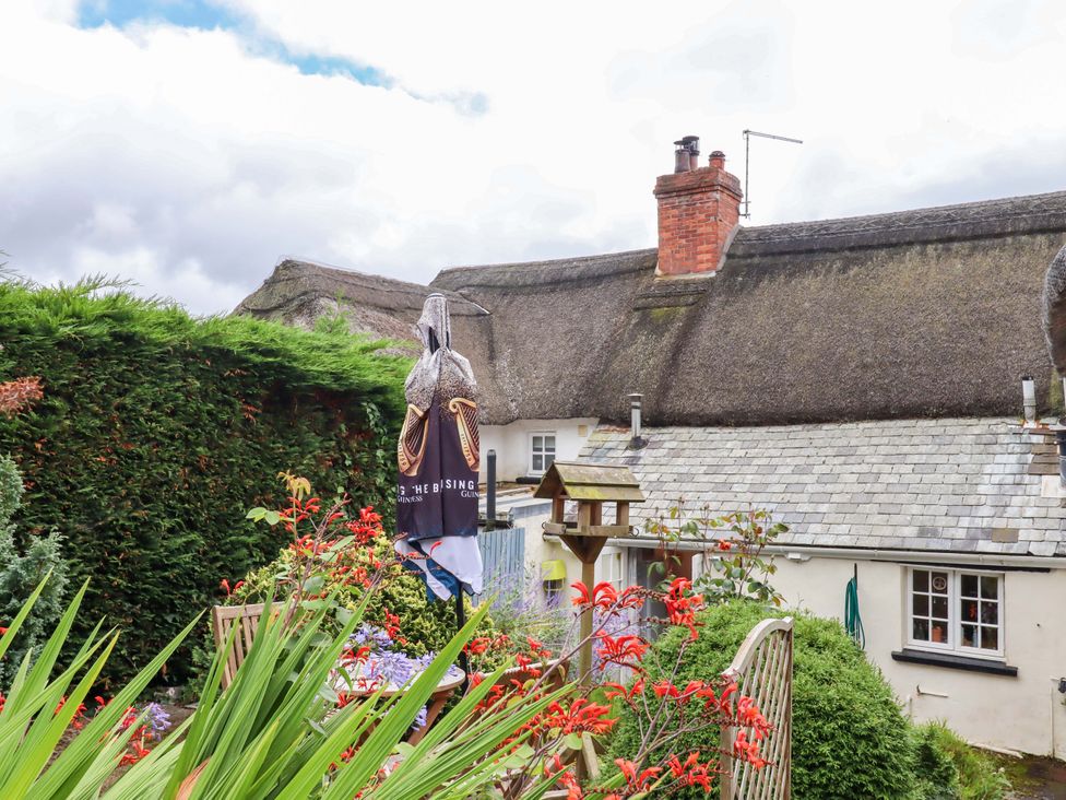 A garden with flowers and a table under an umbrella at Cosy Nook in South Molton