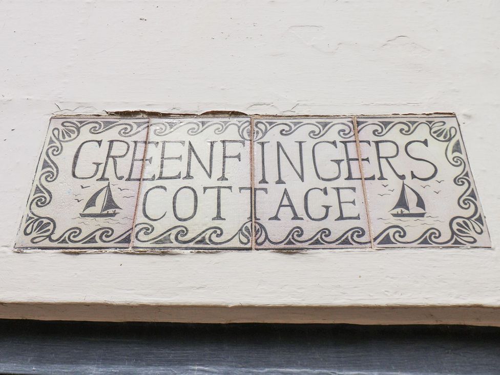 A sign that reads 'GREENFINGERS COTTAGE' on a wall at Greenfingers in Whitby