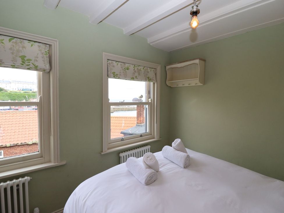 A bedroom with a bed and windows at Greenfingers in Whitby