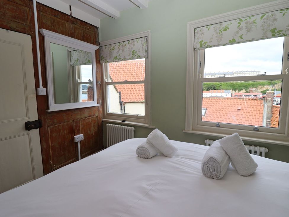 A bedroom with a bed and windows at Greenfingers in Whitby
