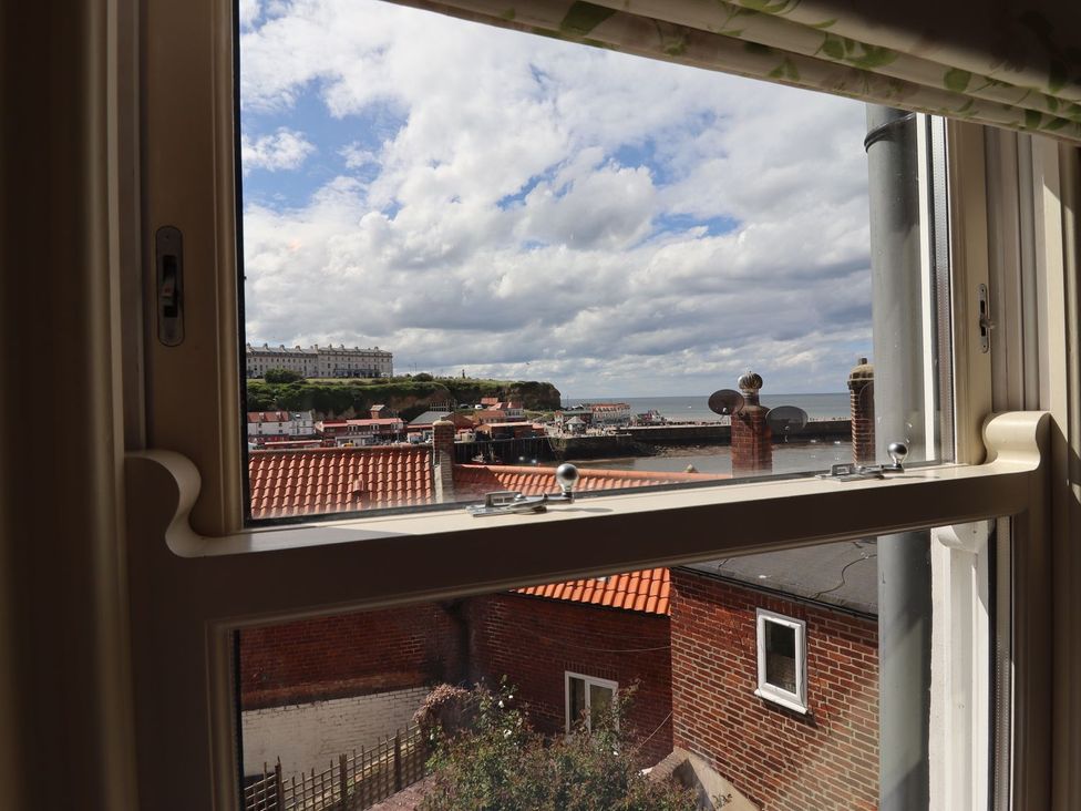 A view from a window showing rooftops and the sea at Greenfingers in Whitby