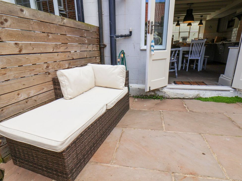 An outdoor patio with a sofa and door leading to the kitchen at Greenfingers in Whitby