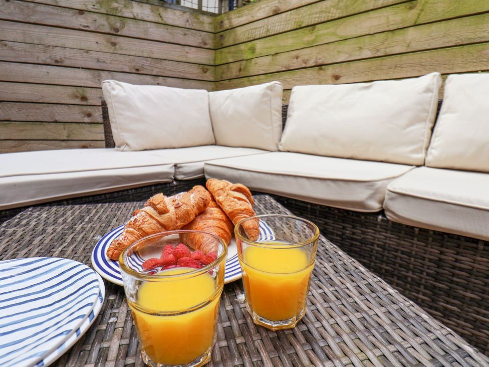 An outdoor seating area with cushions, croissants, raspberries, and orange juice at Greenfingers in Whitby