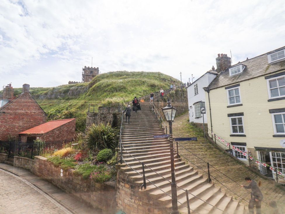 A staircase leading up to a hill with houses and flowers at Greenfingers in Whitby