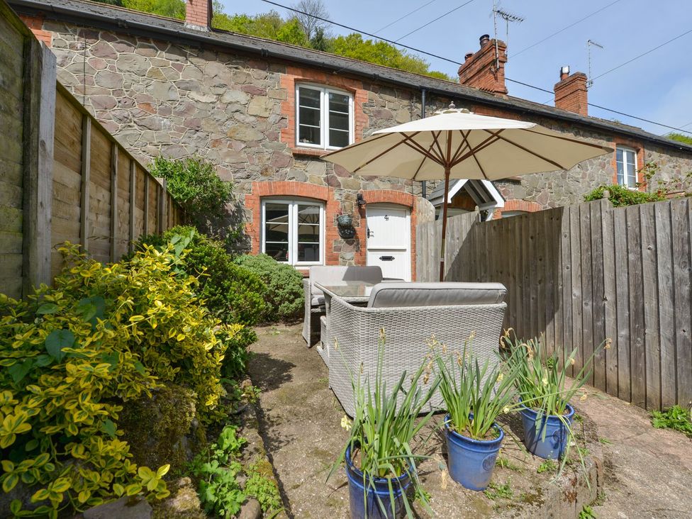 A garden with a couch and umbrella at Woodedge in Minehead