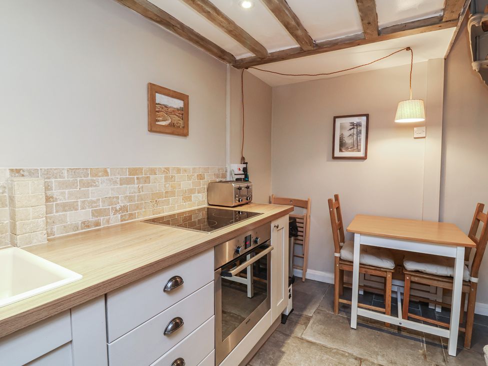 A kitchen with a countertop, stove, oven, and table at Woodedge in Porlock