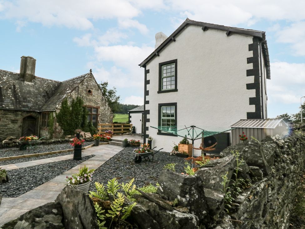 A garden with flowers and a two-story house at Holy Trinity Cottage in Millom