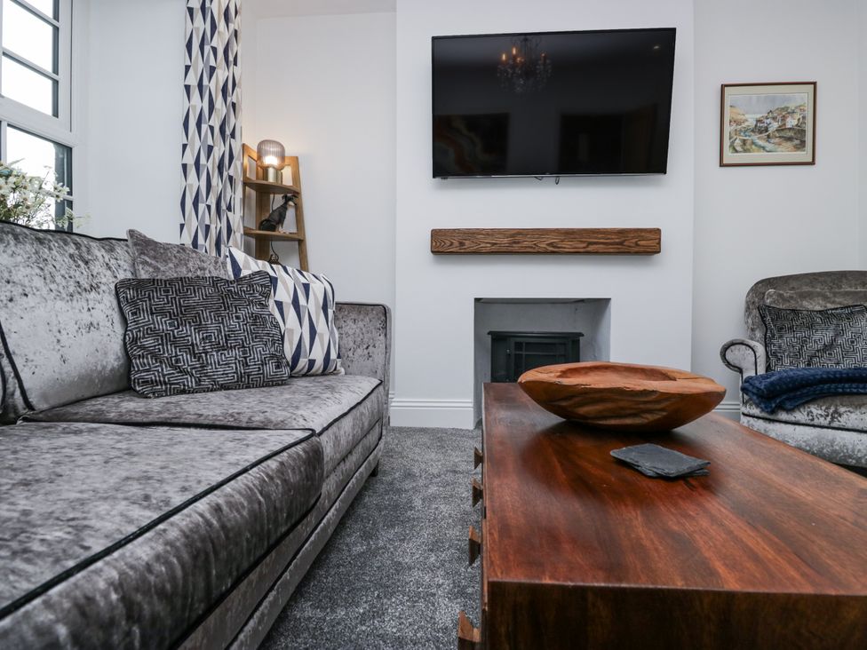 A living room with a sofa, armchair, and coffee table at Holy Trinity Cottage in Millom