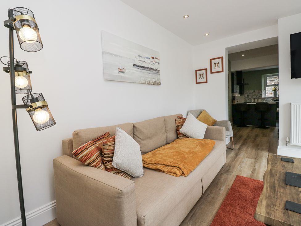 A living room with a sofa, lamp, and wall art at Holy Trinity Cottage in Millom