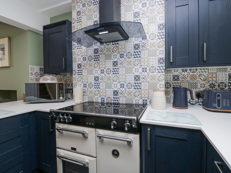 A kitchen with an oven, microwave and storage cabinets at Holy Trinity Cottage in Millom