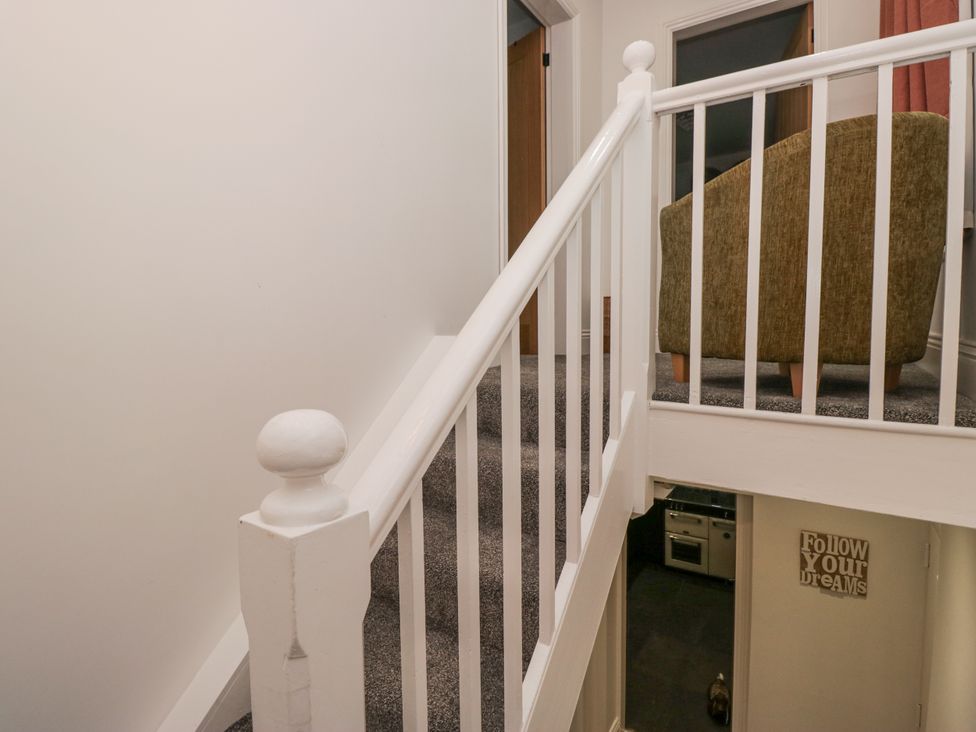A staircase landing with a handrail and a chair at Holy Trinity Cottage in Millom