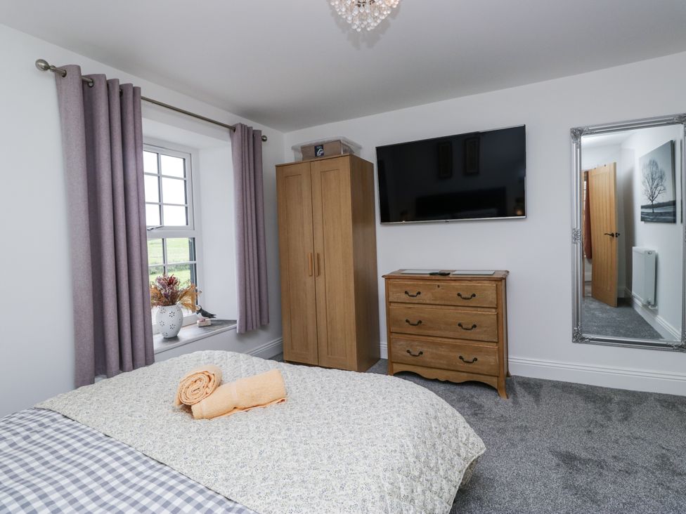 A bedroom with a bed and wardrobe at Holy Trinity Cottage Millom