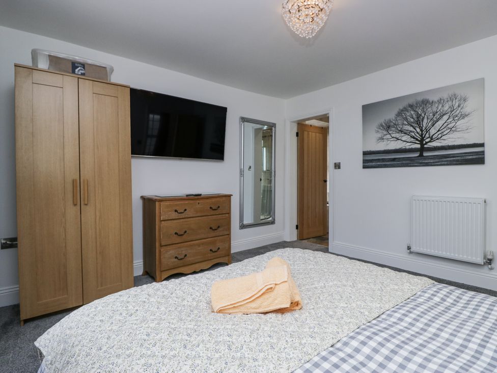 A bedroom with a wardrobe and a chest of drawers at Holy Trinity Cottage in Millom