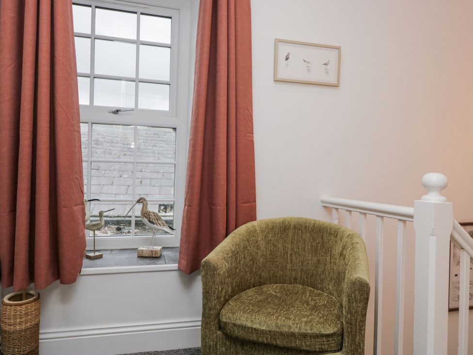 A staircase landing with a chair and a window at Holy Trinity Cottage in Millom