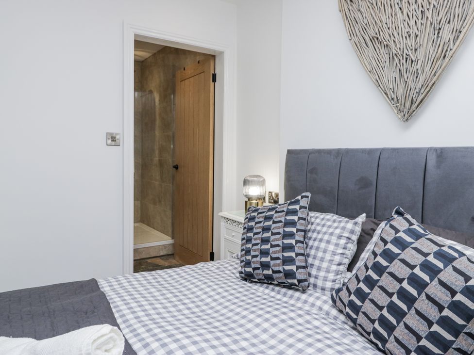 A bedroom with a bed and attached shower at Holy Trinity Cottage in Millom