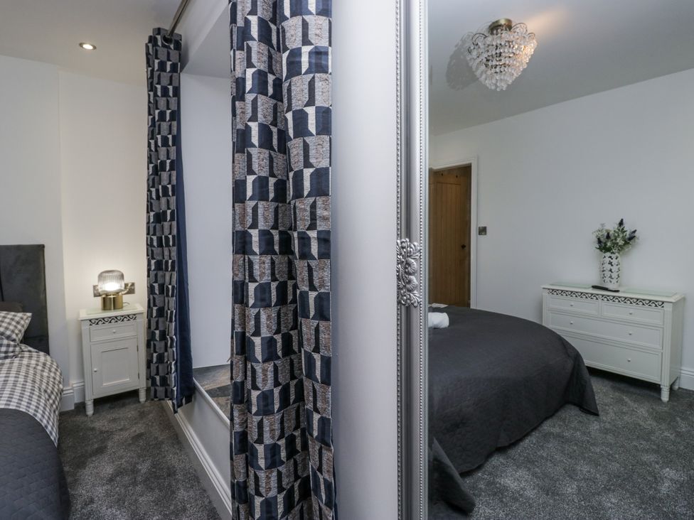 A bedroom featuring a bed, lamp, and dresser at Holy Trinity Cottage in Millom