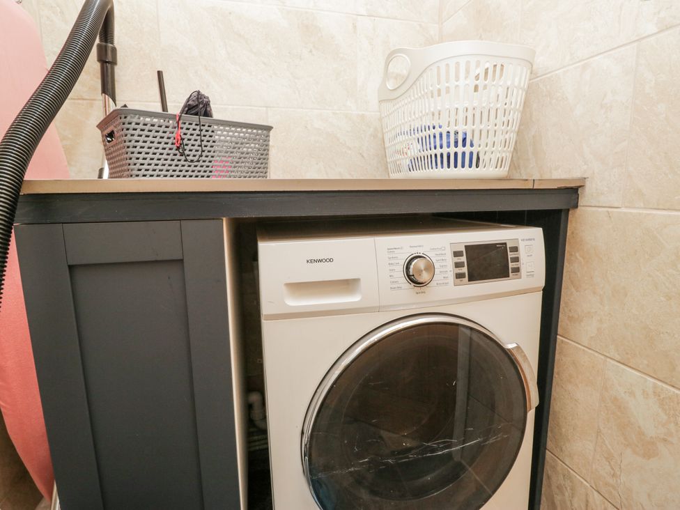 A laundry room with a washing machine and laundry baskets at Holy Trinity Cottage in Millom