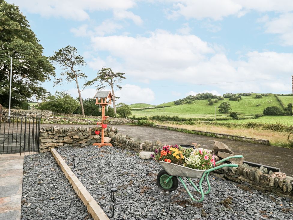 An outdoor area with a wheelbarrow of flowers at Holy Trinity Cottage Millom