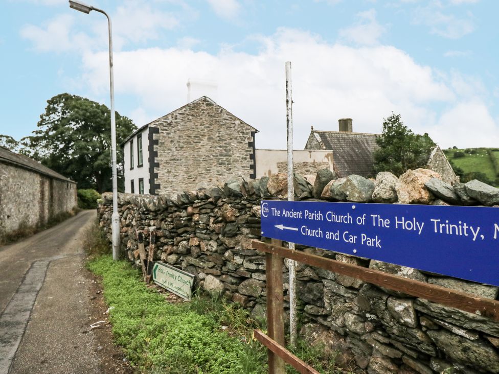 A sign pointing to Holy Trinity Church near a road and stone wall at Holy Trinity Cottage, Millom