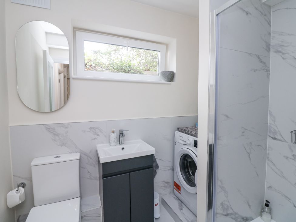 A bathroom with a toilet, sink, washer, and shower at 7 Belfort Court