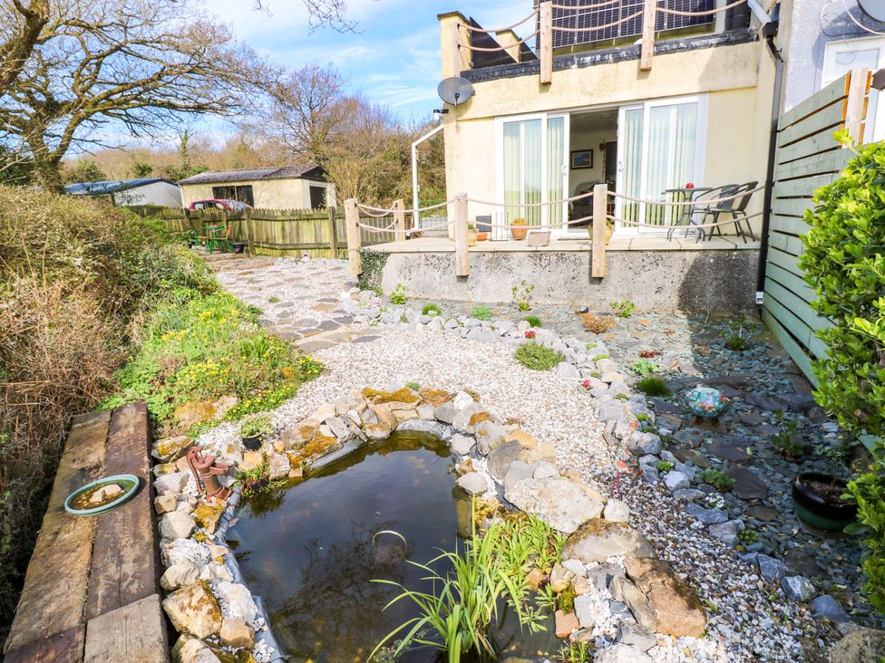 A garden with a pond and seating area at No.51 Llanteg Park in Amroth