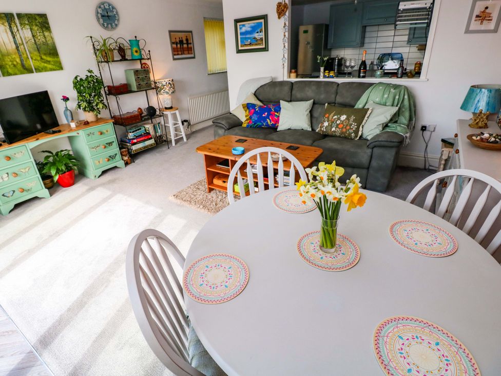 A living room with a sofa and dining area at No.51 Llanteg Park in Amroth