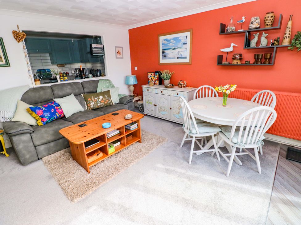 A living room with a sofa, coffee table, and dining area at No.51 Llanteg Park Amroth