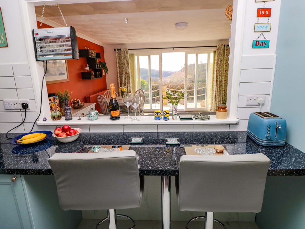 A kitchen with bar stools and a view in No.51 Llanteg Park, Amroth