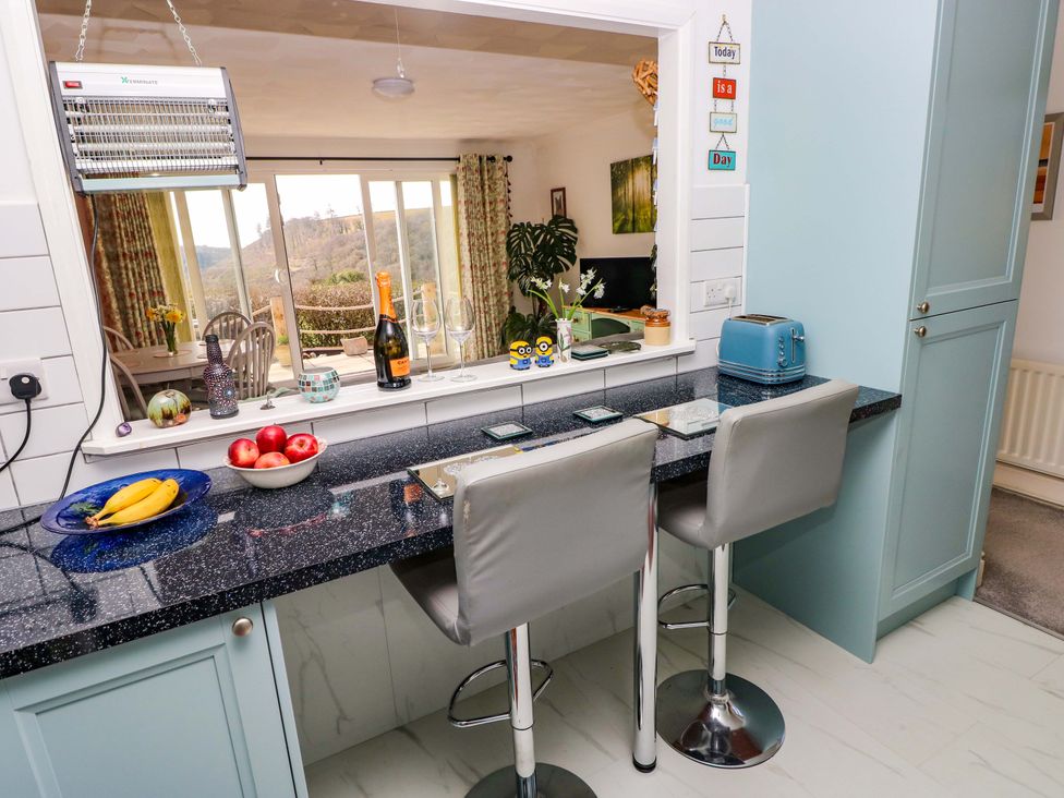 A kitchen with a counter and bar stools at No.51 Llanteg Park Amroth