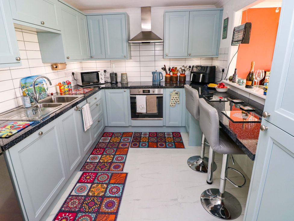A kitchen with countertop appliances and bar stools at No.51 Llanteg Park, Amroth